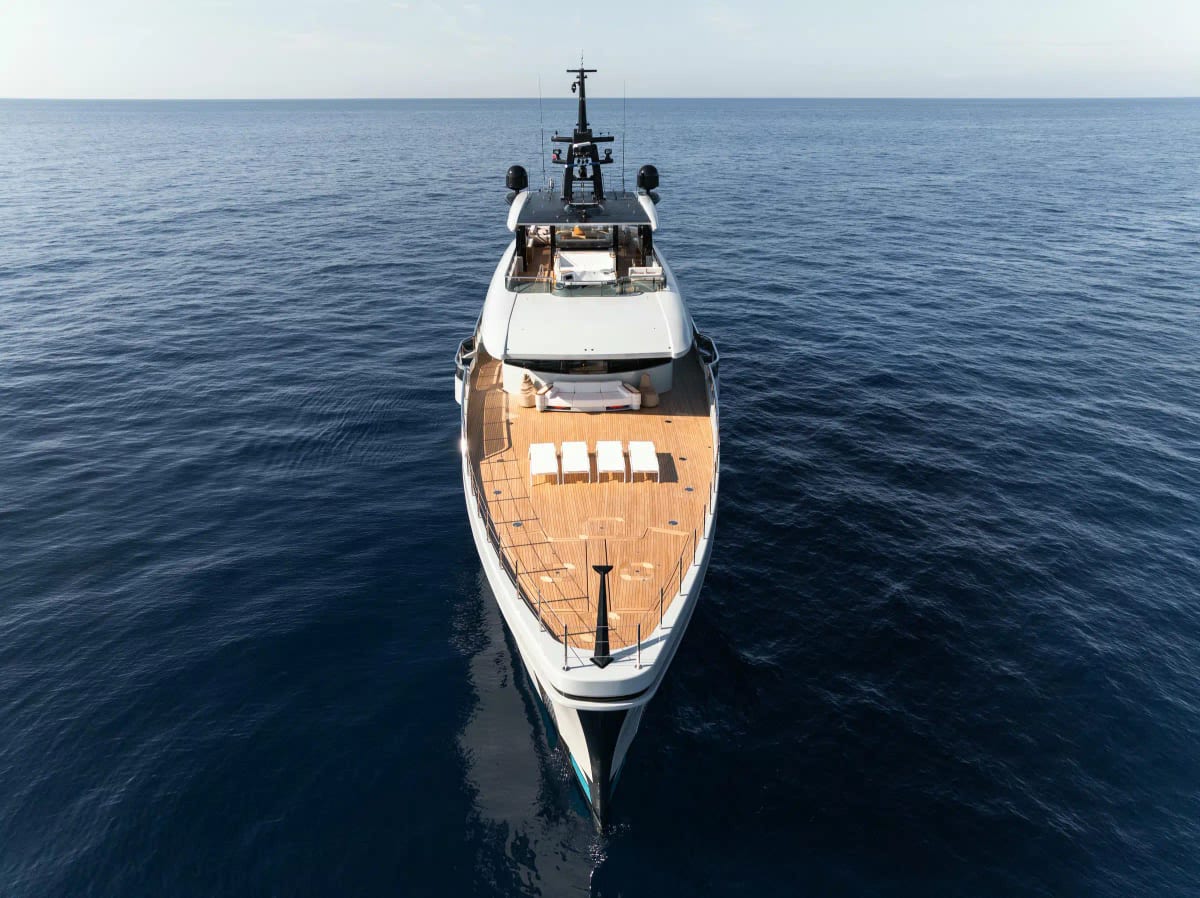 Superyacht seen from above, teak deck and wake on deep blue water